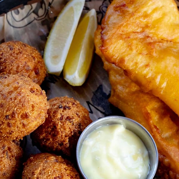 Crispy fried fish, hush puppies, lemon wedges, and a side of tartar sauce from BBQ King Smokehouse.